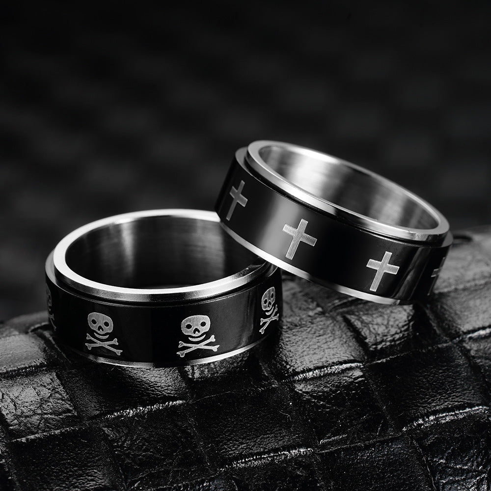 Titanium fidget ring for anxiety featuring skull and cross designs on a sleek black surface.